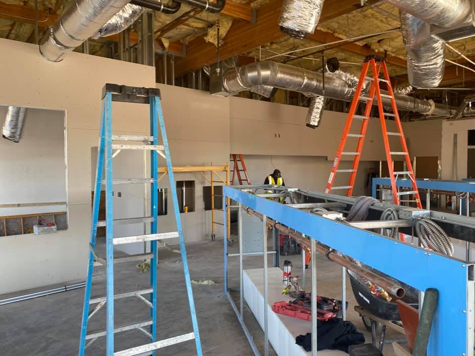 Beginning stages of indoor construction of WaveMax Laundry. 2 ladders with laundry machine built-ins.